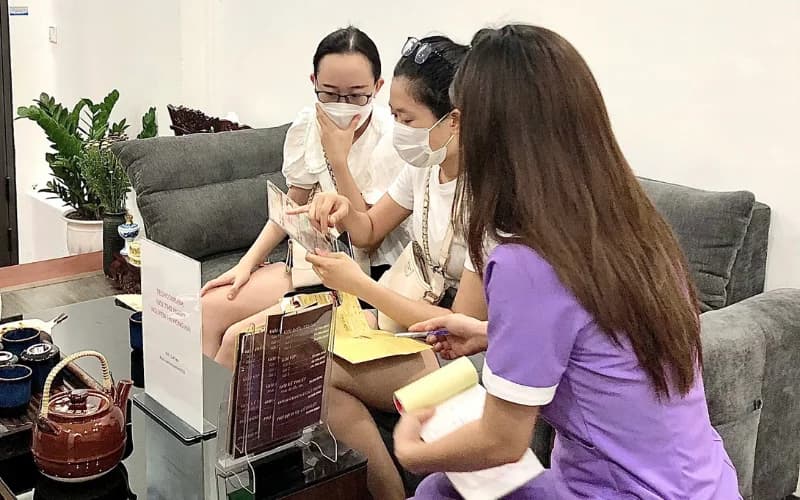 Nhân viên tư vấn liệu trình, khách xem bảng dịch vụ
