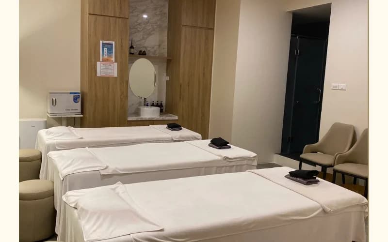 Phòng massage tập thể sạch sẽ, giường phủ khăn trắng.